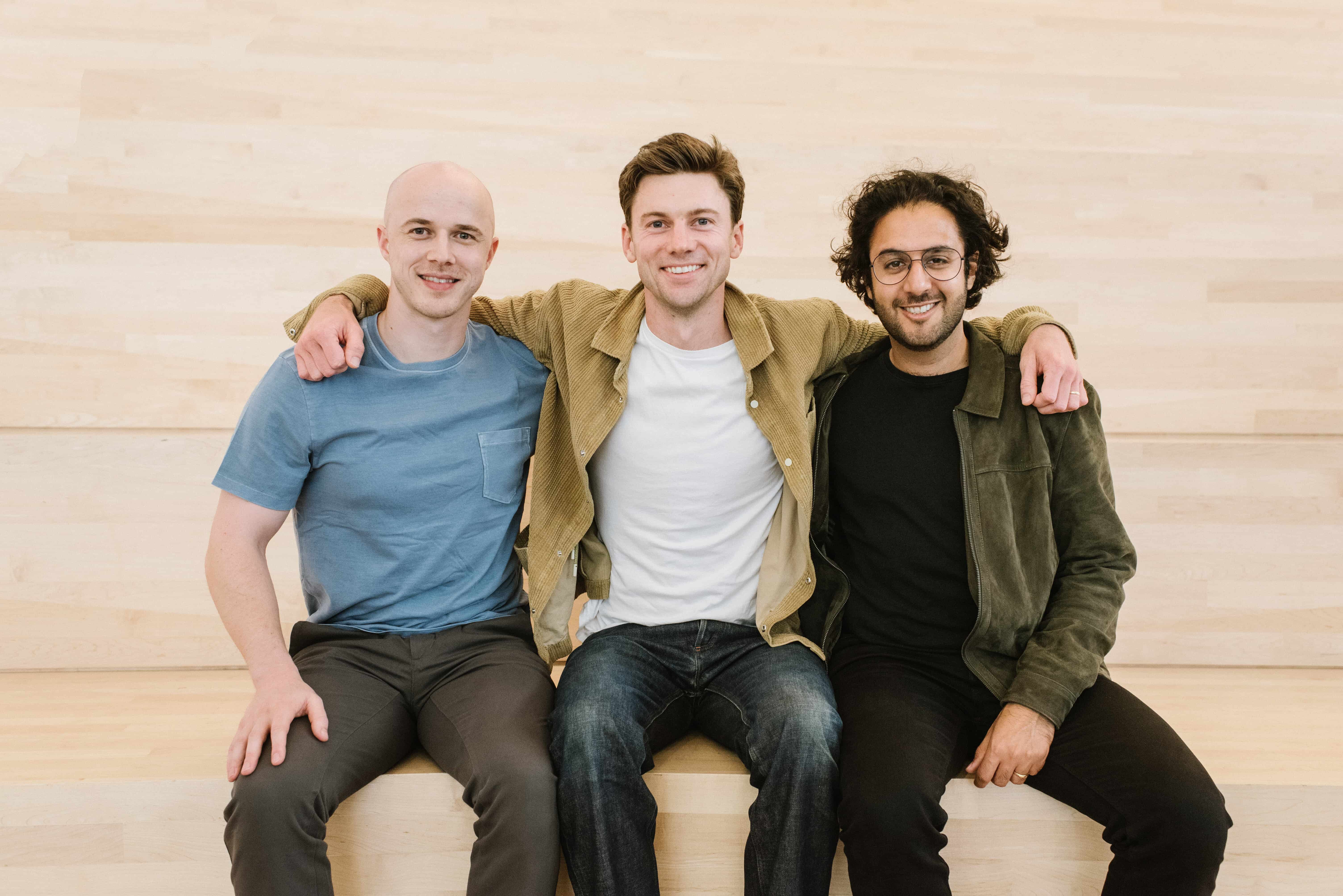 Three Humanloop founders seated together against a pale wood wall